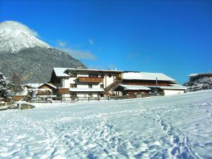 ein schneebedecktes Gebäude vor einem Berg in der Unterkunft Ferienwohnungen Krismer in Arzl im Pitztal