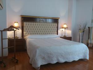 a bedroom with a white bed with two tables and two lamps at Hotel Cardinal in Albacete