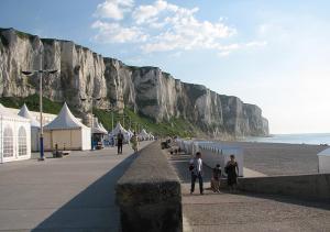 a group of people walking along a beach with a mountain at Les Mouettes in Le Tréport