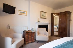 um quarto com uma cama e uma cadeira e uma televisão em Bramwood Guest House em Pickering
