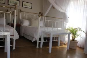 1 dormitorio con cama blanca y mesa en Ashbourne Hazyview, en Hazyview
