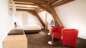 a bedroom with a bed and a red chair at Hotel Hofgut Hohenkarpfen in Hausen ob Verena