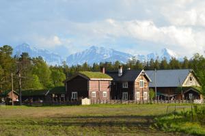 a group of houses in a field with mountains in the background at Kvebergsøya Gard in Grimsbu
