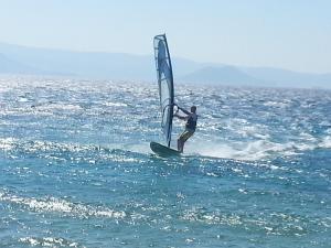 a man riding a wind sail on the ocean at Karades Houses Poseidon 75m2 in Naxos Chora