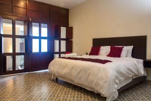 una grande camera da letto con un grande letto con cuscini rossi di Hotel Maculís a Campeche
