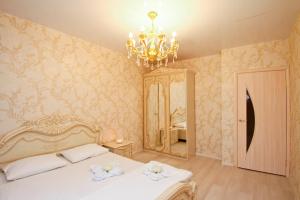 a bedroom with a bed and a chandelier and a mirror at Centre Apartments - Surgut in Surgut