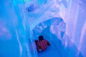 a person sitting in a fake ice cave at Hotel de Glace in Saint-Gabriel-De-Valcartier