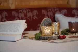 einen Tisch mit einem Buch und Kerzen und einen Teller mit Lichtern in der Unterkunft Landhaus Schatz in Nesselwängle