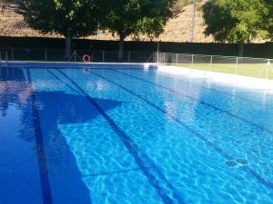 a large blue swimming pool with trees in the background at Arroyo Milano Casa Rural in Maello