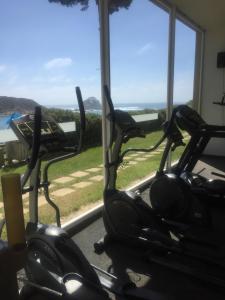 eine Reihe von Cardio-Bikes in einem Fitnessraum mit Fenstern in der Unterkunft Departamento Pinares del Canelillo in Algarrobo