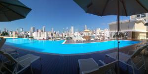 una gran piscina con sillas y sombrillas en un edificio en Home Clube em Balneário Camboriú, en Balneário Camboriú