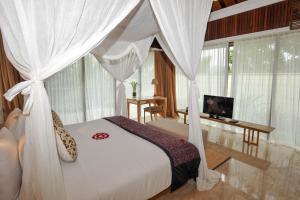 a bedroom with a white bed with a canopy at Komaneka at Rasa Sayang Ubud in Ubud