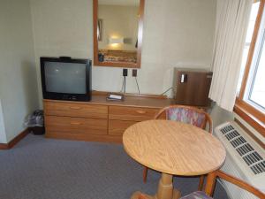a room with a table and a television on a dresser at Town & Country Motor Inn in Lake Placid