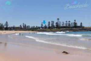 a beach with a couple of surfers on it at Bluewater Apartments in Kiama