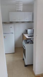 a white kitchen with a stove and a refrigerator at Apartamentos del Este in Piriápolis