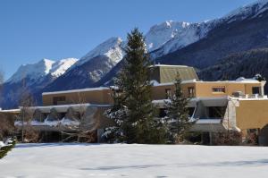 un bâtiment dans la neige avec des montagnes en arrière-plan dans l'établissement Tulai D74, à Scuol