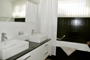 La salle de bains est pourvue de 2 lavabos, d'une baignoire et d'un miroir. dans l'établissement Tulai D74, à Scuol