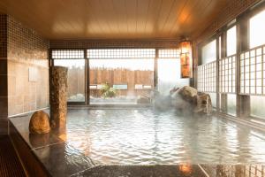 a large pool of water with rocks in a building at Dormy Inn Matsuyama Natural Hot Spring in Matsuyama