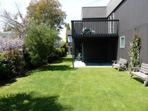 a house with a green yard with two benches at Brylin Motel in Rotorua