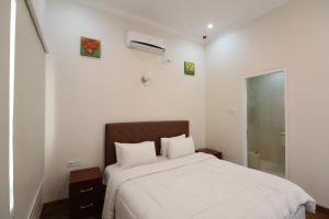 a white bedroom with a bed and a window at Diyar Villas Puncak M6/50 in Puncak