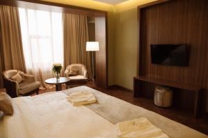 ein Hotelzimmer mit einem Bett und einem TV in der Unterkunft Garden Park Inn in Almaty