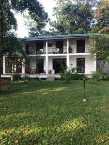 a white building with a yard in front of it at Villa by the Lake Bolgoda, Moratuwa-Colombo in Moratuwa