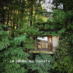 a cabin in the middle of trees with a balcony at La Cabane aux Secrets - Au Milieu de Nulle Part in Outines