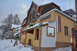 a building with a sign on it in the snow at Penzion Bublava in Bublava
