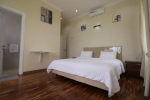 a bedroom with a large white bed and wooden floors at Diyar Villas Puncak NB3/3 in Puncak