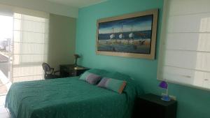 a bedroom with a green bed and a painting on the wall at Condominio Las Terrazas in Asia