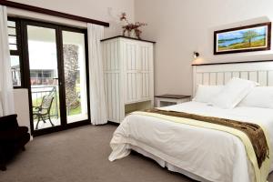 um quarto com uma grande cama branca e uma varanda em Riviera Hotel & Chalets em Velddrif