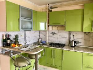 a green kitchen with green cabinets and a table and chairs at Apartments in the center in Truskavets