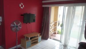 a room with a red wall with a television and a fan at Durban Accommodation 118 Summersands in Durban