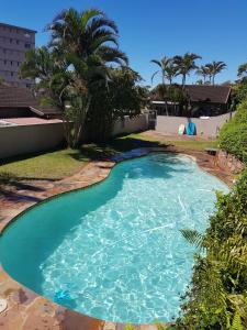 una piscina con agua azul y una palmera en 11 Villa Del Sol, en Amanzimtoti