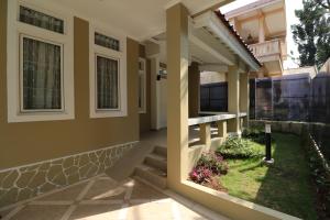een veranda aan de voorzijde van een huis met een tuin bij Diyar Villas Puncak R7-3 in Puncak