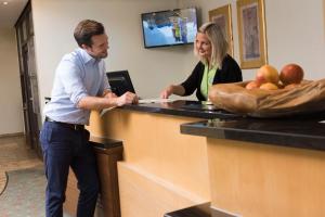 a man and a woman standing at a counter at AHORN Waldhotel Altenberg in Kurort Altenberg