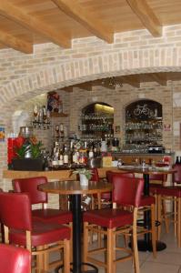 Hôtel - Restaurant Au Tonnelier في بيرج: بار به طاولات خشبية وكراسي حمراء