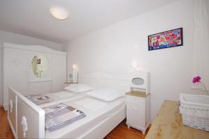 a white bedroom with a bed and a mirror at Apartment Lisa in Zadar