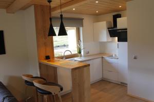 a kitchen with white cabinets and a counter with stools at Chaty pod Beskidkiem in Szczyrk