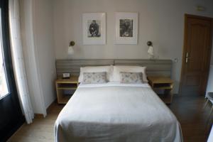 a bedroom with a large white bed with two tables at Hostal Santa Cruz in Madrid