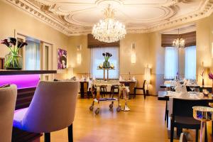 a dining room with tables and chairs and a chandelier at Alden Suite Hotel Splügenschloss Zurich in Zurich