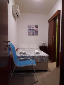 a blue chair in a room with a bed at Marina's Rooms in Larnaca