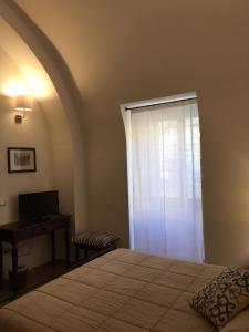 a bedroom with a bed and a window with a desk at B&B Macrina in Noto