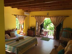 a bedroom with a bed and a balcony at Linsen Selfcatering Apartments in La Digue