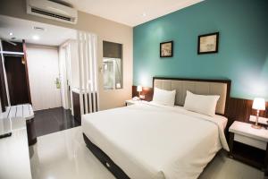 1 dormitorio con 1 cama grande y pared azul en Happy Inn, en Yakarta
