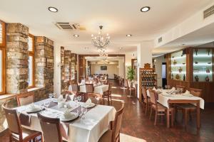a restaurant with white tables and chairs and a chandelier at Hotel Gino Wellness Rabath in Akhaltsikhe