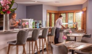 two people standing at a bar in a restaurant at Mallory Court Country House Hotel & Spa in Leamington Spa