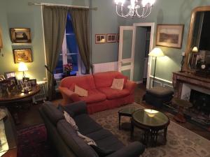 a living room with a red couch and a fireplace at Chateau de Beaulieu in Saint-Sauveur-le-Vicomte
