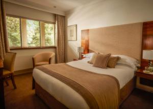 a hotel room with a large bed and a window at Mallory Court Country House Hotel & Spa in Leamington Spa