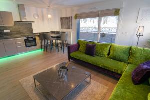 Una sala de estar con un sofá verde y una cocina. en La Niche, en Brides-les-Bains